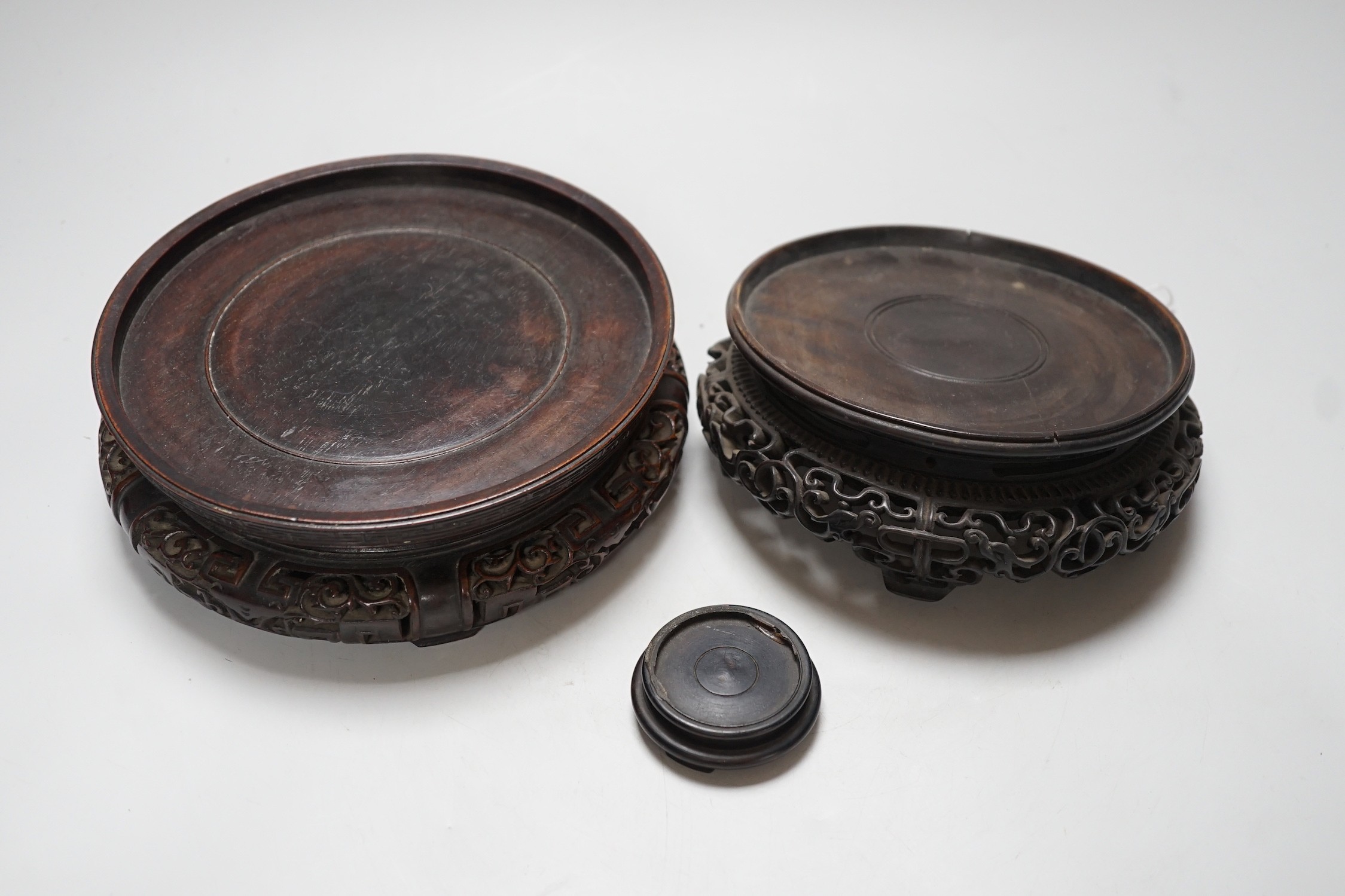 Three Chinese carved hardwood stands, largest 19cm
